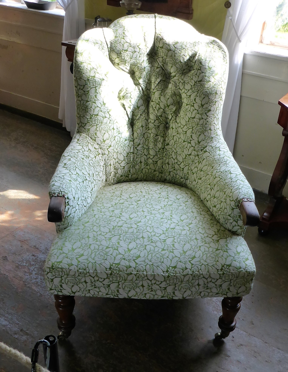 Stolen har en ramme av tre med dreide frambein som er beiset og oljet.