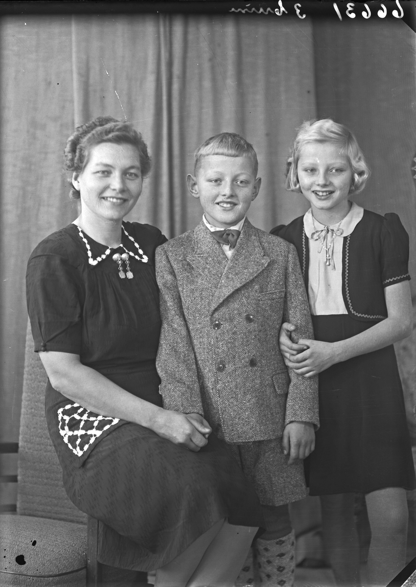Portrett. Familiegruppe på tre. Ung kvinne, ung pike og ung gutt. Bestilt av Fru Christie Nordalh. Mølstrevåg.