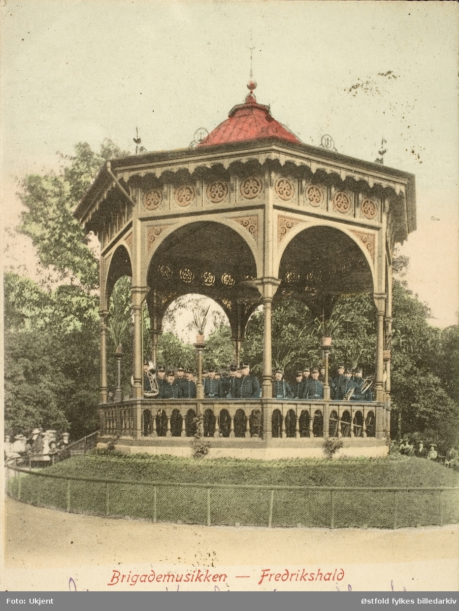 Postkort, kolorert lystrykk av paviljong i Halden der Brigademusikken spiller, 1903.