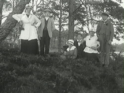 Ungdomar, tre kvinnor och tre män, poserar i en skogsdunge vid en sjö.