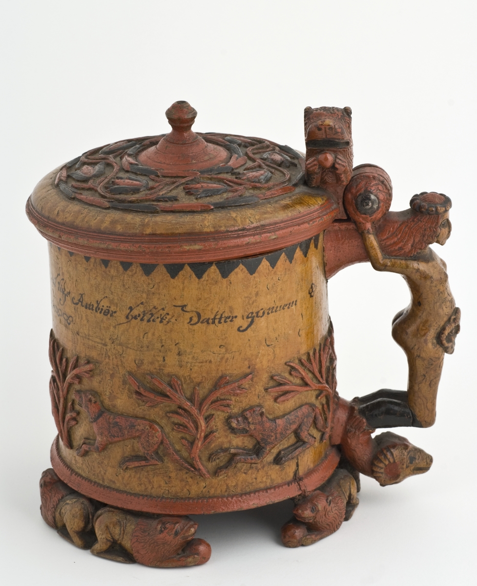 Dekorert med fortløpende billedfrise med dyr og trær på nederste del av korpus. Kannen har løveføtter og løvegjekk og bakkantine som håndtak. 