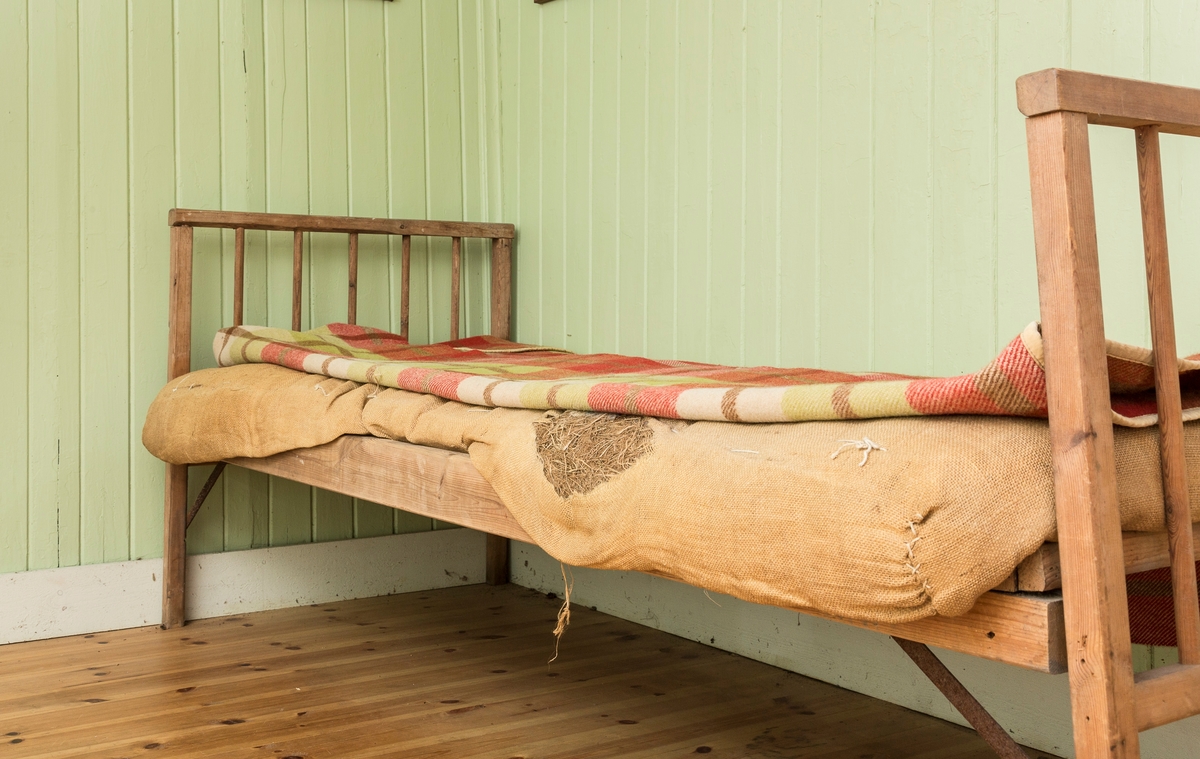 Sengeramme med sangegavler bestående av staver. Ubehandlet tre. Avstivere i metall. Nettingbunn.