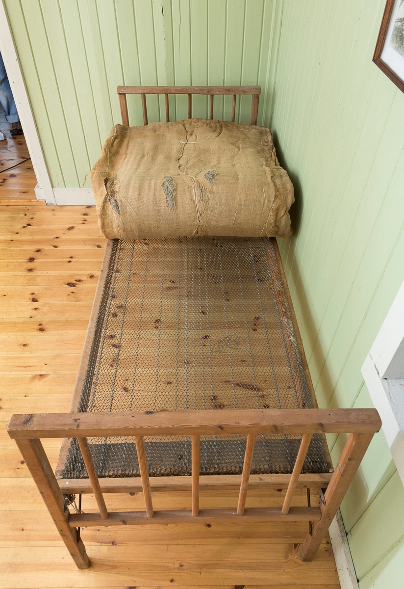 Sengeramme med sangegavler bestående av staver. Ubehandlet tre. Avstivere i metall. Nettingbunn.