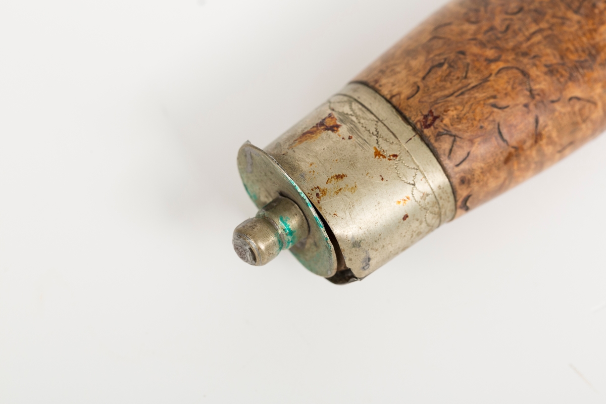 Tollekniv av tradisjonell norsk/nordisk type. Håndsmidd laminert blad med nedsvingt spiss og to dekorhakk innerst på ryggen. Store bruksspor med slagmerker på rygg og hakk i bladet. Store rustpartier. Gjennomgående ulimt tange med tapp til slirestropp. Skaft i valbjørk. Håndlagde loddede holker, mest sansynlig av nysølv (legering av messing, kobber og zink), med trambulerte dekorborder. Bladholken er løs. På toppholken har loddingen løsnet helt slik at toppen er totalt adskilt fra sidedelen av holken. 

Bladet er stemplet L.S. I følge Norsk knivforening kan dette være
Skålbø, Lars Sondresen 1850-1940, NO-01547, Tinn / Telemark
Kategori: Smed, Kjennetegn: Stemplet  LS (skjønnskrift), LS og L.S. TINN. på knivbladene.