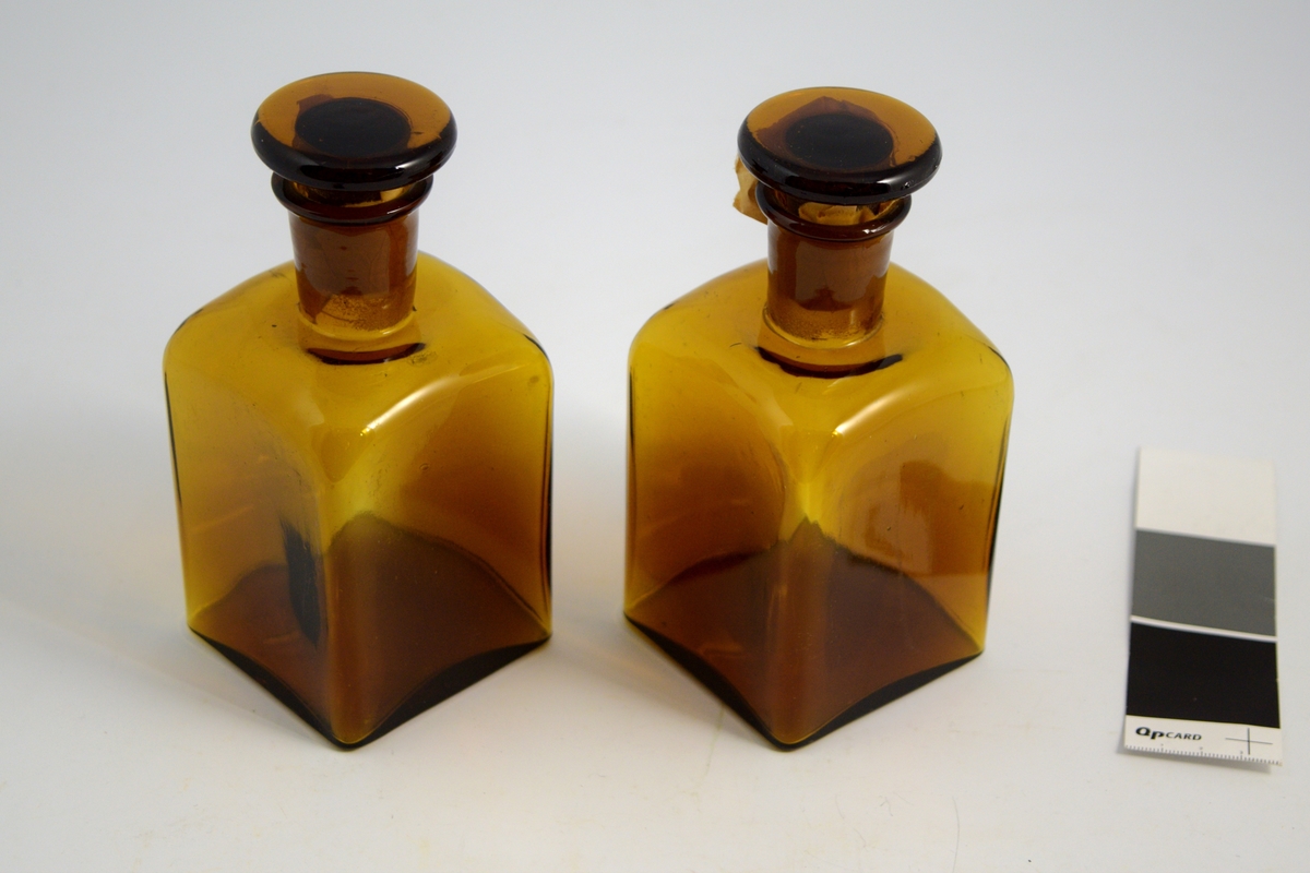Brun firkantet liten glassflaske med propp. Brukt til oppbevaring og slag av flytende. 2 stk.