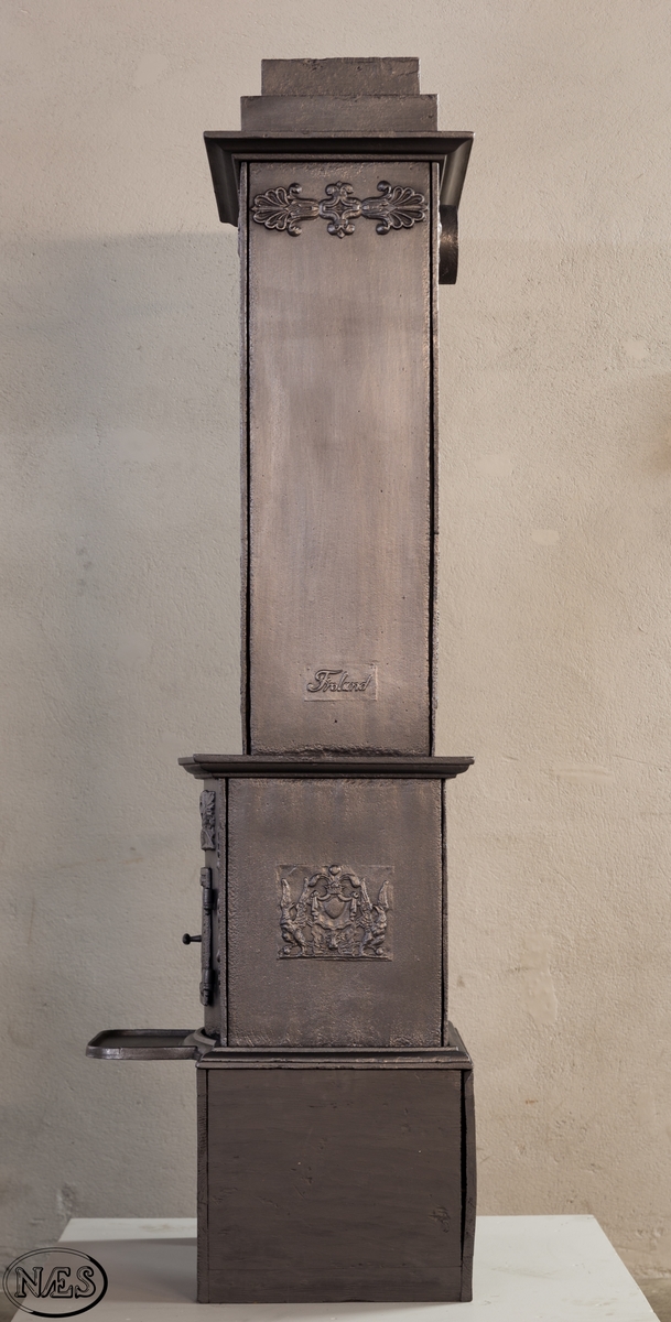 Ovnen består av to avdelinger. Underdelen har et frembuet midtparti med kamskjell flankert av sjødyr på hver side. På kortsidene skjold, løvehode og symmetriske ørner. På bakplate en krukke med symmetriske engler.
Overdelen er høy, firkantet med tredelt åpning. Empire ornamentikk og avtrappet topp. Øverst på frontplaten symetriske fabeldyr (pegasus) vendt mot hverandre.