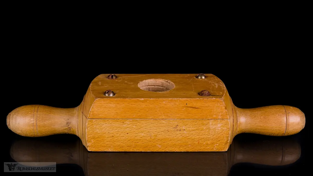 Rektangulær trekloss bestående av to deler som er festet til hverandre med skruer. En V- formet kniv er festet mellom delene og stikker fram i det gjennomgående hullet hvor treemnene gjenges. Et lite sponhus er skåret ut i skjøten mellom de to delene. Dreide trehåndtak på hver side.