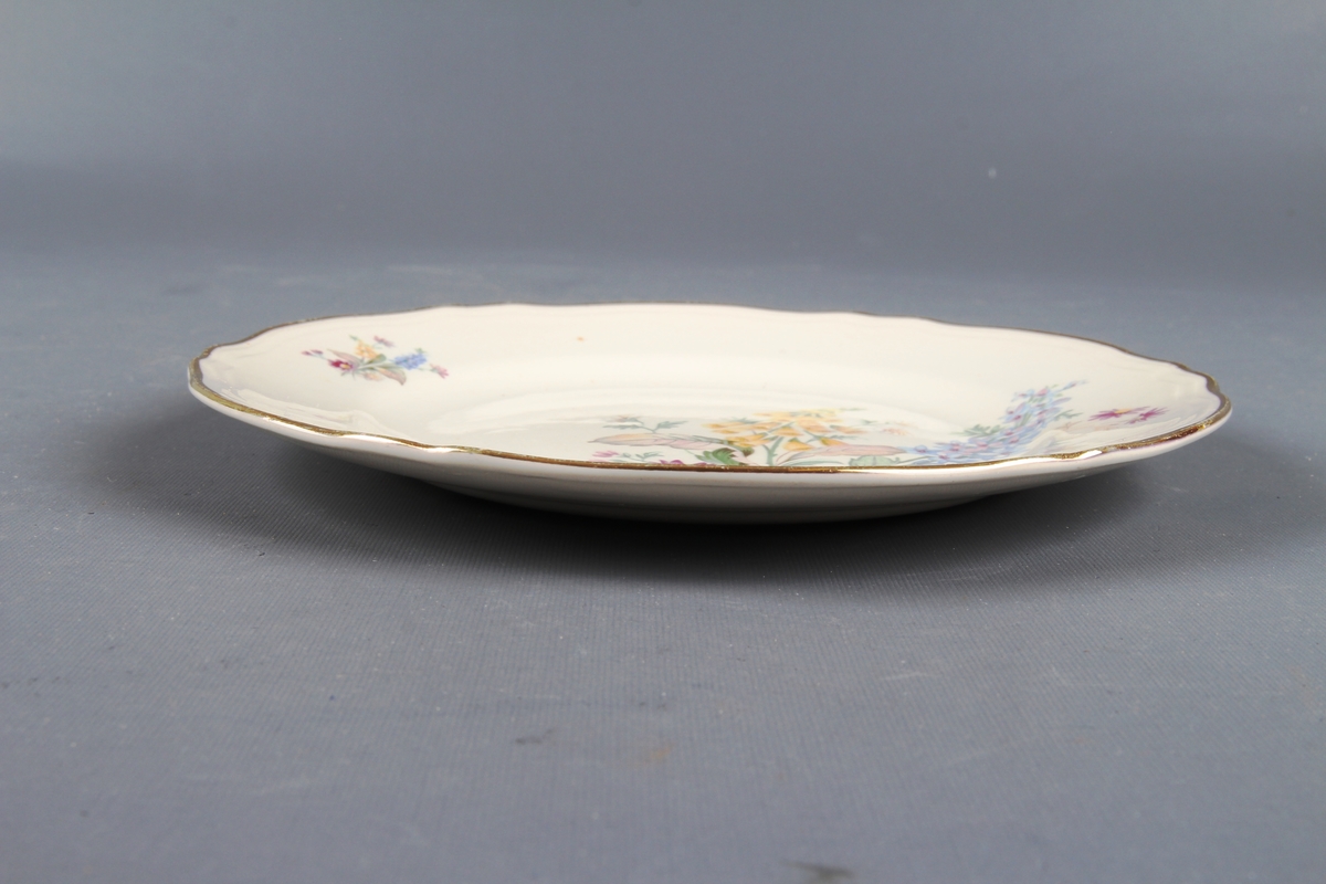 Tallerken med blomsterdekor og gullkant ytterst.