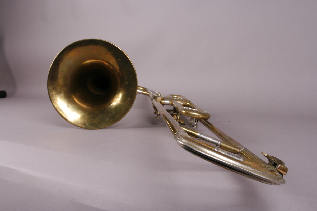 Ventilbasun, eller trombone, i messing, med dreieventiler. Tilhørende munnstykke.
