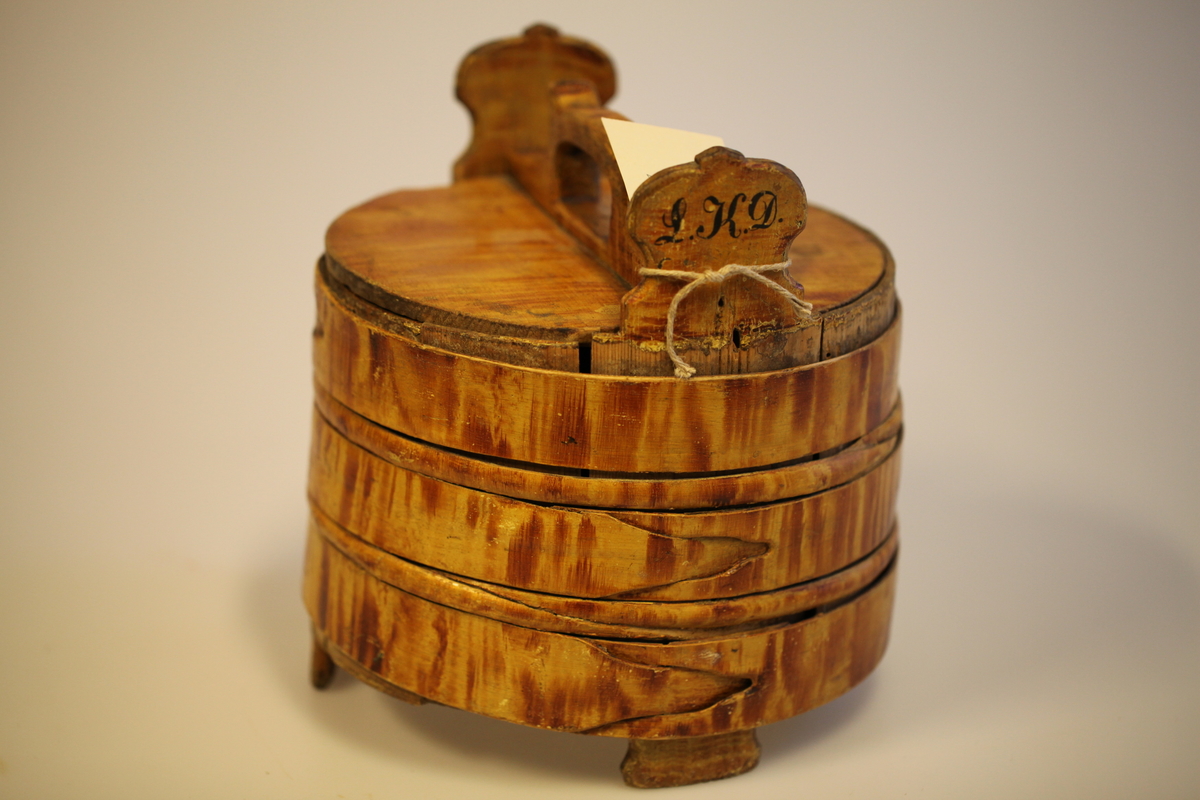 Lagging belagt med tette sveiperinger. Lokk, to ører  og tre bein. Formen er rund, lokk er nedfelt og har avlang hank. Sveip med skjøter (5 stk.) (gjorder). Påmalt gyllengul farge, ådringsmalt.