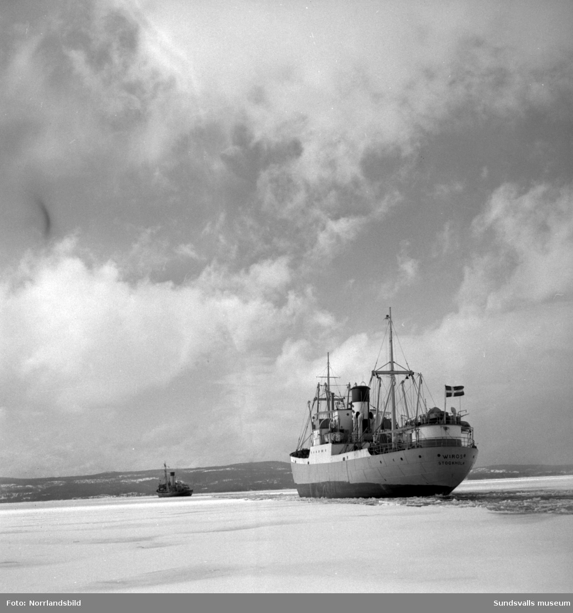 Isbrytaren Atle bryter isränna för Stockholmsbåten Wiros förbi fyren Draghällan och in mot Sundsvalls hamn.
