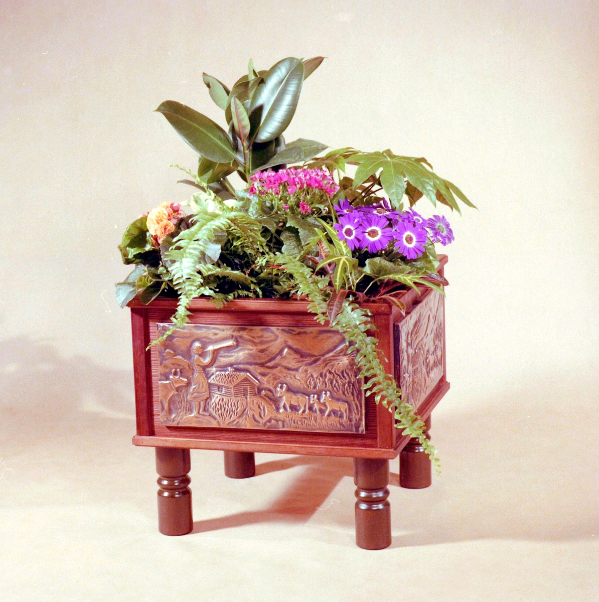 Blomster-/ plantekasse i tre med utskorne motiv på sidene.