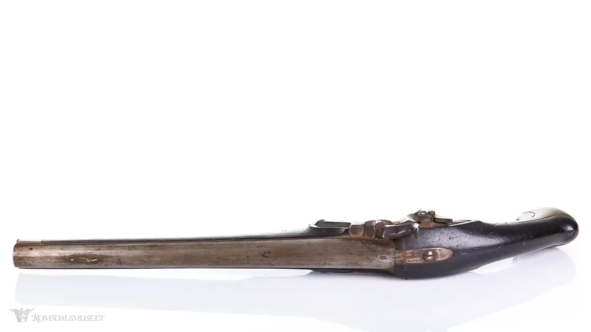 Flintlåspistol med glattboret løp, uten baksikte og med åpent korn. Skjefte av bøk med messingbeslag i enden og ved munningen. To røkner med ladestokk.