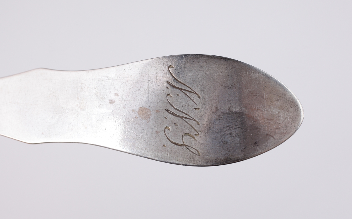 Matsked i silver, 
Fiolmodell, slät med ås. Ägarinitialer: "N.N.S." på baksidan av skaftet. Stämplar på ovansidan av skaftet.