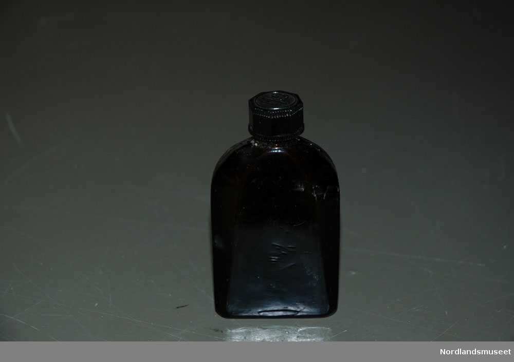 Brun medisinflaske i glass. Den har en kork på toppen for å skrue den opp.Under flasken står det "Nivea".