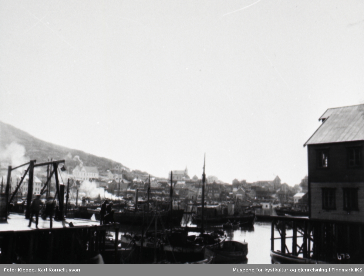 Honningsvåg. Havnebilde med båter, deler av bebyggelsen og kirka i bakgrunnen. 'Galge' på kaia. 1923 eller 1935.