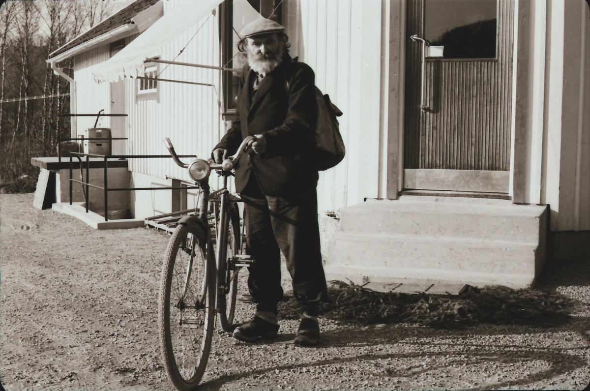 Kloar-Erik med cykel utanför "Filialen", en lokal handelsbod.