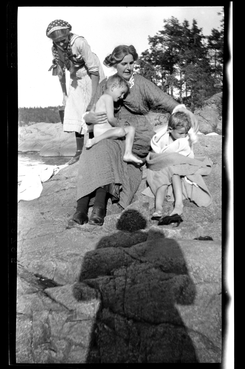 Ant. Hilda Sundt sitter på et svaberg med to gutter som har badet, en jente står bak.