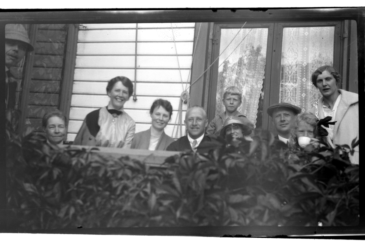 Ukjente personer, Elisabeth Sundt, Rolf Sundt, Bjarne T. Sundt, Olive Sundt, Finn Sundt, Allis Anker Sundt og Hilda Sundt sitter på verandaen på Farøy.  Fotografert 1918–1919.