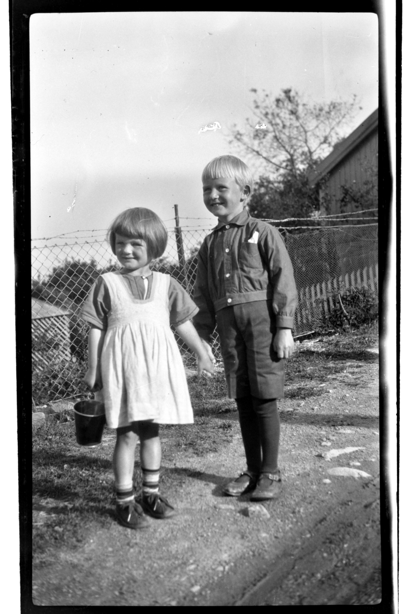 En jente og en gutt står hånd i hånd, begge ukjente. Fotografert 1922.