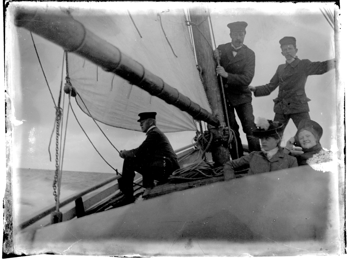 To kvinner og tre menn i seilbåt. Antagelig fotografert 1903-04.