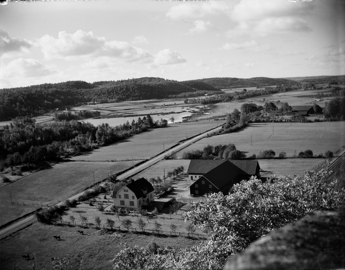 Vy över jordbrukslandskapet och Viskan mot Järlövs gård med Lövagård närmast i bild. Lövagårds tomt kantas av späda lövträd.