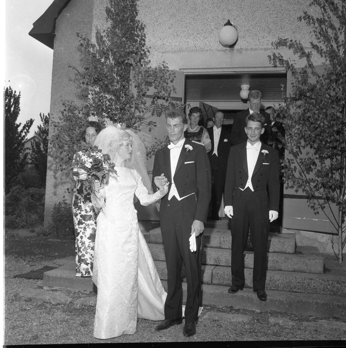 Nygifta Rolf Nilsson och Lisbeth Johansson utanför Örserums kyrka. Till vänster om bruden står hennes syster Birgit Johansson och till höger om brudgummen står Göran Malm.