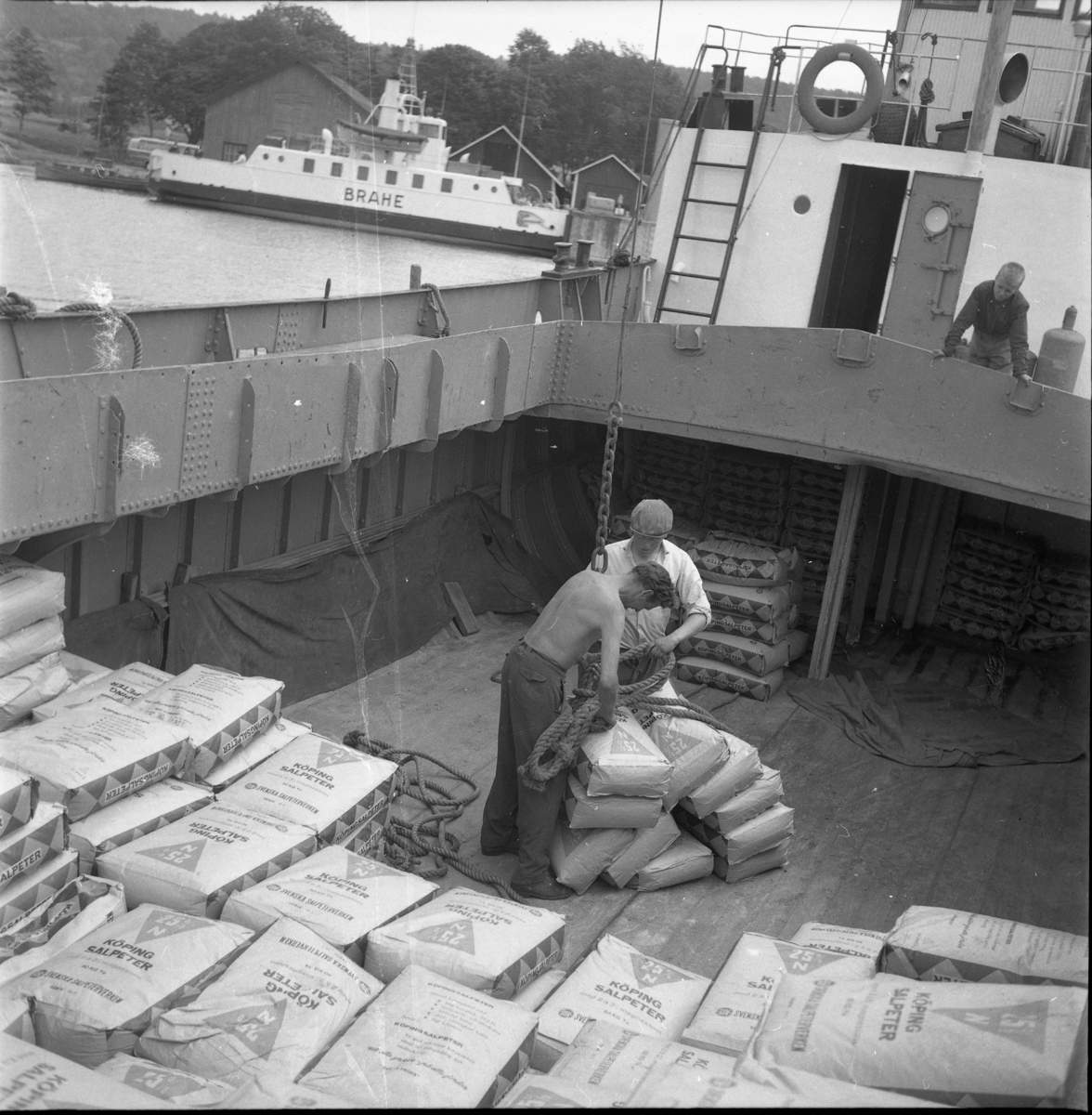 Oidentifierade personer lossar kalksalpeter från skutan Gullmar i Gränna hamn. Gullmars skeppare heter Paul Larsson från Brandstorp. I bakgrunden syns färjan Brahe.