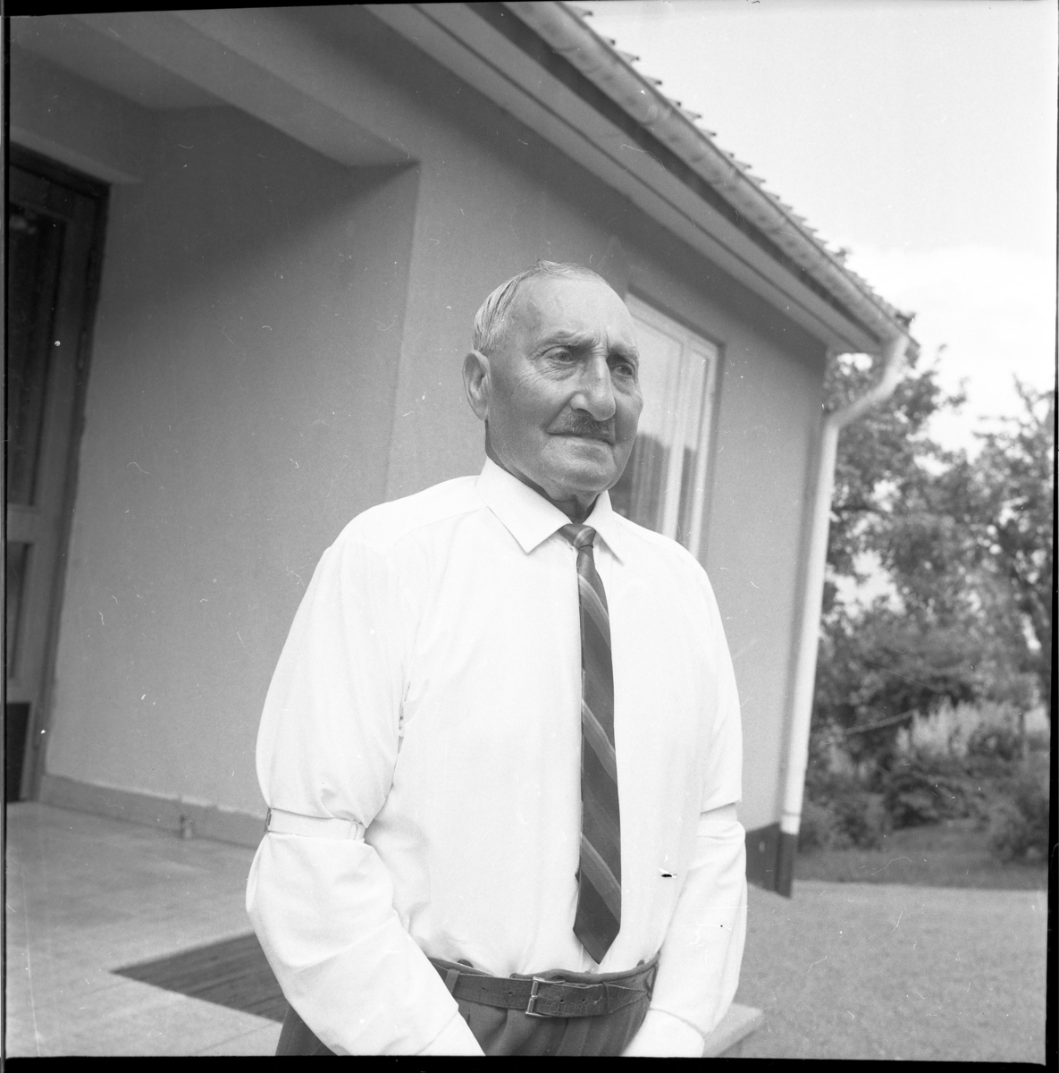 Allvin, en äldre man, stående utanför Mellbyro i vit skjorta och slips på 85-årsdagen.