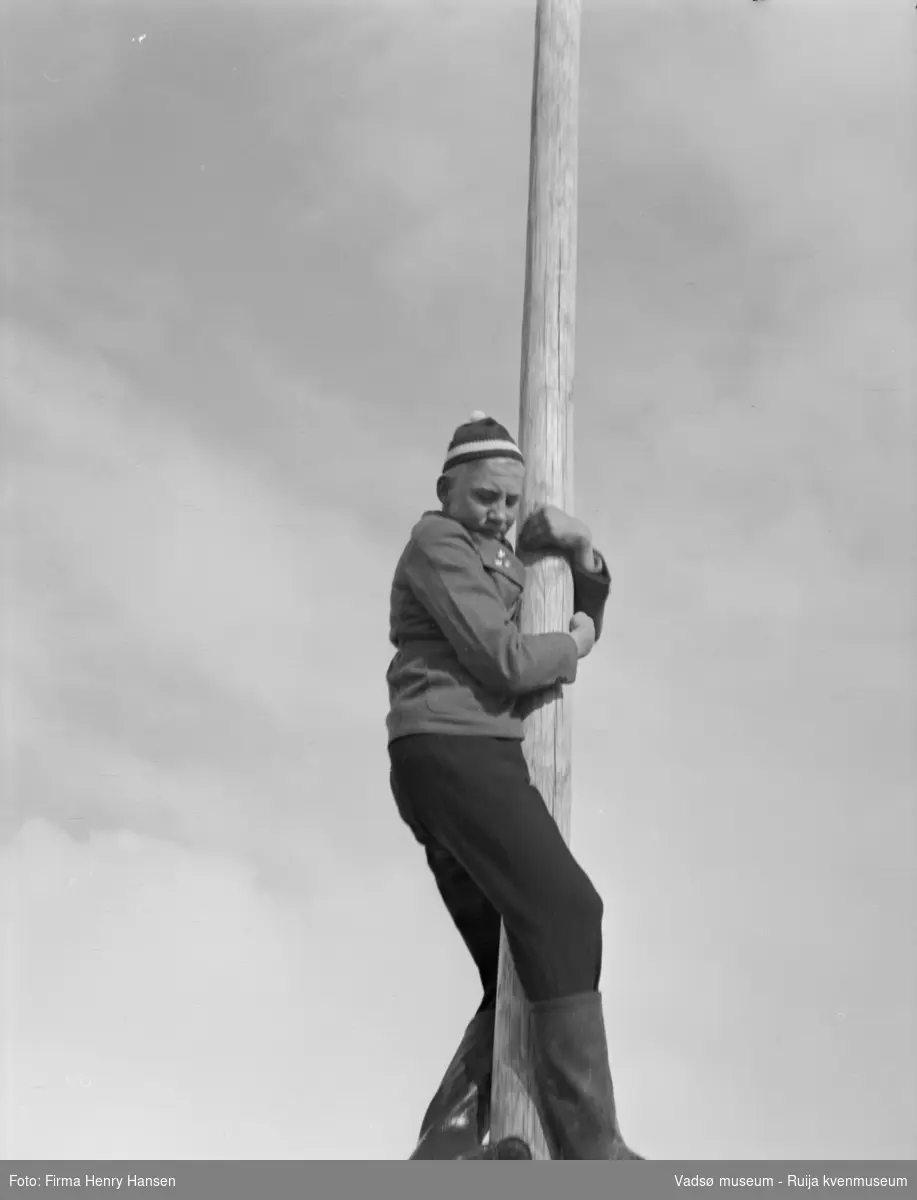 Vadsø 17 mai 1952. Ung gutt i topplue høyt i en flaggstang.
