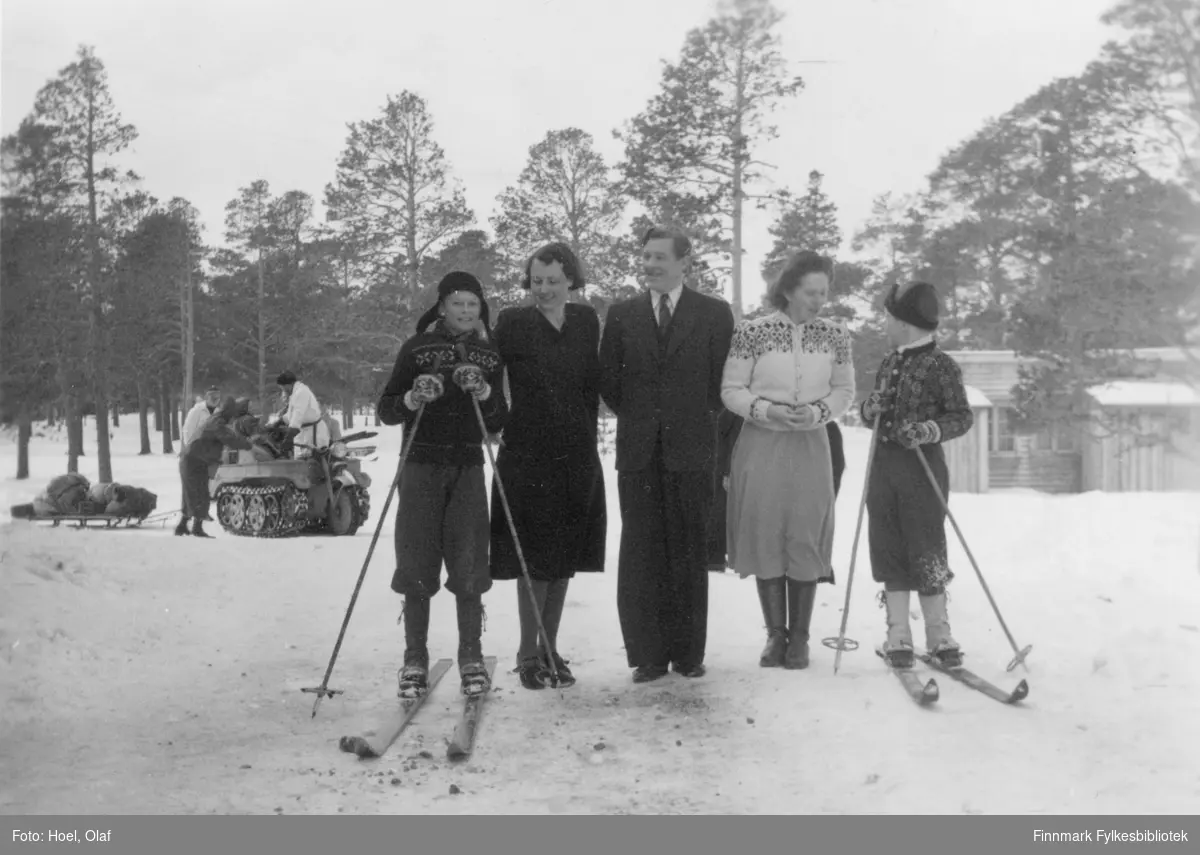 Fra venstre: Kjell F. Hoel, Gunvor Hoel, Ørnulv Vorren, Gerd Vorren og Richard Hoel. Kjell og Richard står på ski. Bak gruppen ser vi en beltevogn og slede og en del av et hus.

Olaf Hoel (1903-1970) var den første rektoren ved fylkets første gymnas Finnmark off. Gymnas i Alta i årene 1948-1952. Kjell F. Hoel har gitt en liten bildesamling etter sin far fra hans tid i Alta til Finnmark fylkesbibliotek. Olaf Hoel gjorde en pionerinnsats for skolen under gjenreisningen av landsdelen etter krigen.