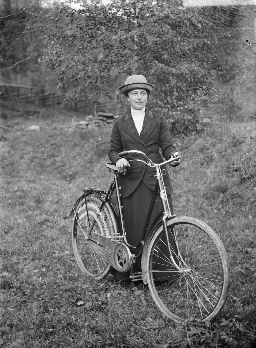 Kvinne med sykkel, merk "Tryg"