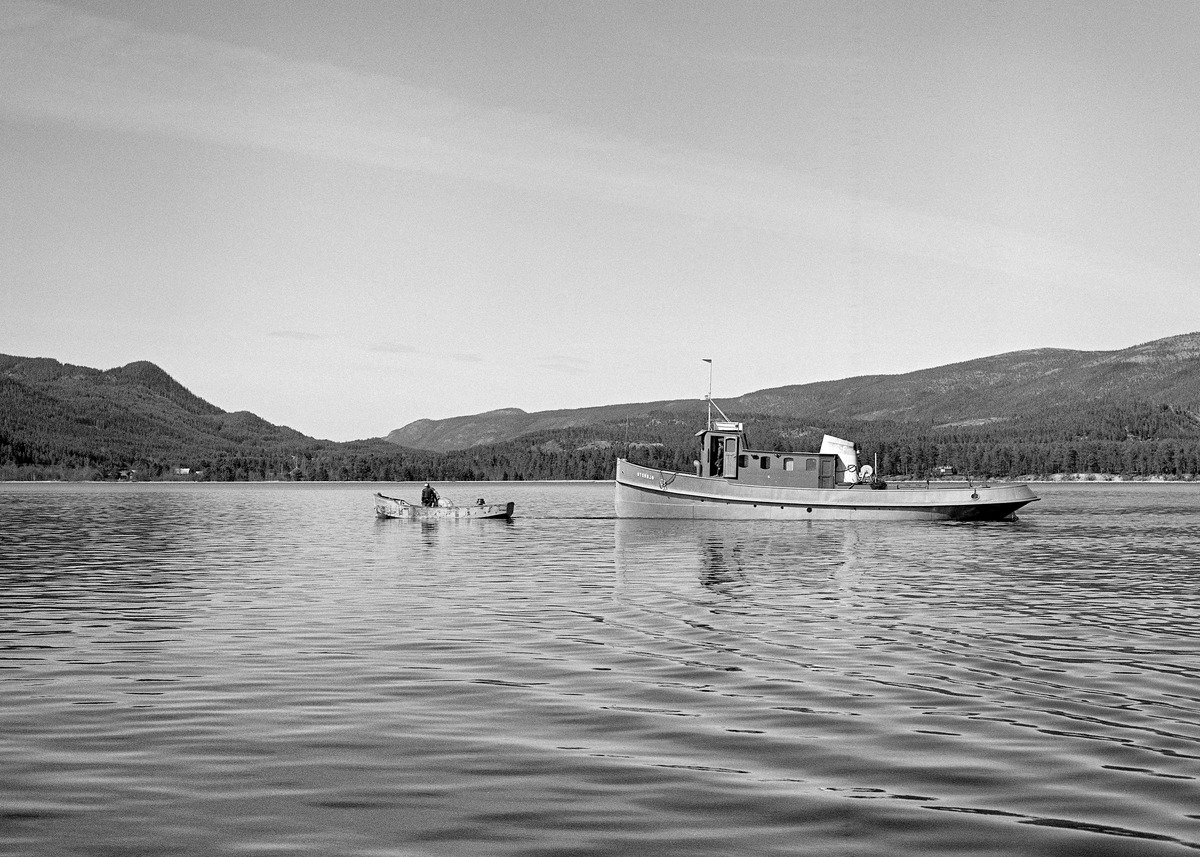Tømmerslepebåten «MS Storsjø» fotografert i nordenden av innsjøen den hadde fått navn etter i Rendalen i Hedmark.  Fotografiet er tatt like etter at båten var sjøsatt i mai 1984, som ble den siste fløtingssesongen i denne delen av Glommavassdraget.  Det lå en varpebåt av stål framfor baugen på det større fartøyet.  Mens Storsjø ble brukt til å buksere store ringbommer sørover den 36 kilometer lange innsjøen, mens varpebåtene ble brukt under landrensk.  Direksjonen (styret) for Christiania Tømmerdirektion (Glomma fellesfløtingsforening) vedtok i 1911 å gå til anskaffelse av en dampslepebåt som kunne brukes til å trekke tømmer i bommer over den lange og djupe Storsjøen. Her hadde det vært vanskelig å få fløtt fram virket i løpet av en sesong, noe som innebar verdiforringelse av tømmeret. Det nye fartøyet ble kontrahert fra Glommens mek. Verksted i Fredrikstad. I mangel av farbar vannveg mellom verftet og sjøen der båten skulle brukes ble komponentene fraktet med tog til Koppang. Derfra ble de trukket på sleder over til Burua i Ytre Rendalen, hvor komponentene ble klinket sammen. D/S Storsjø fikk en lengde på 58 fot 6 tommer og en bredde på 12 fot.  Den stakk 6 fot ned i vannet ved vanlig belastning.  Båten ble satt i drift våren 1912 og gikk som tømmersleper i Rendalen fram til 1984.  Mer informasjon om denne slepebåten og det transportsystemet den inngikk i finnes under fanen «Opplysninger».