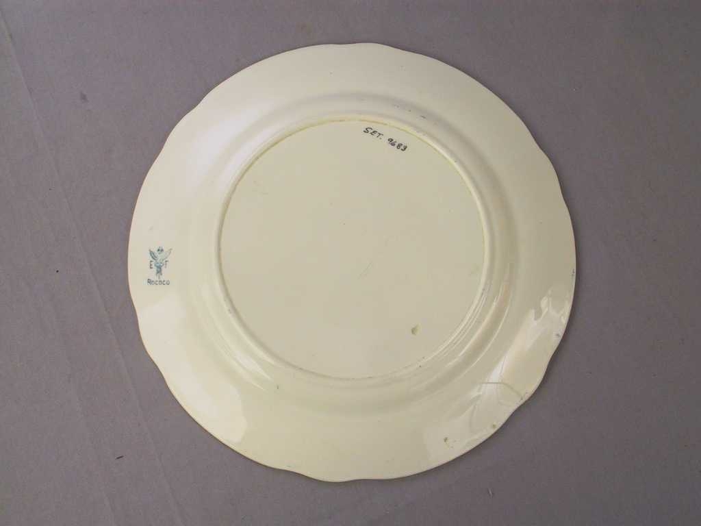 Sirkulært tverrsnitt

Bladornamentikk i relieff rundt kanten. Blå bord rundt kanten og 3 blomemotiv i same farge inni tallerken.
