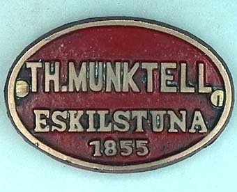 Oval skylt i mässing med text i relief på rödmålad botten:
"TH.MUNKTELL
  ESKILSTUNA
      1855".
Från loket Fryckstad.