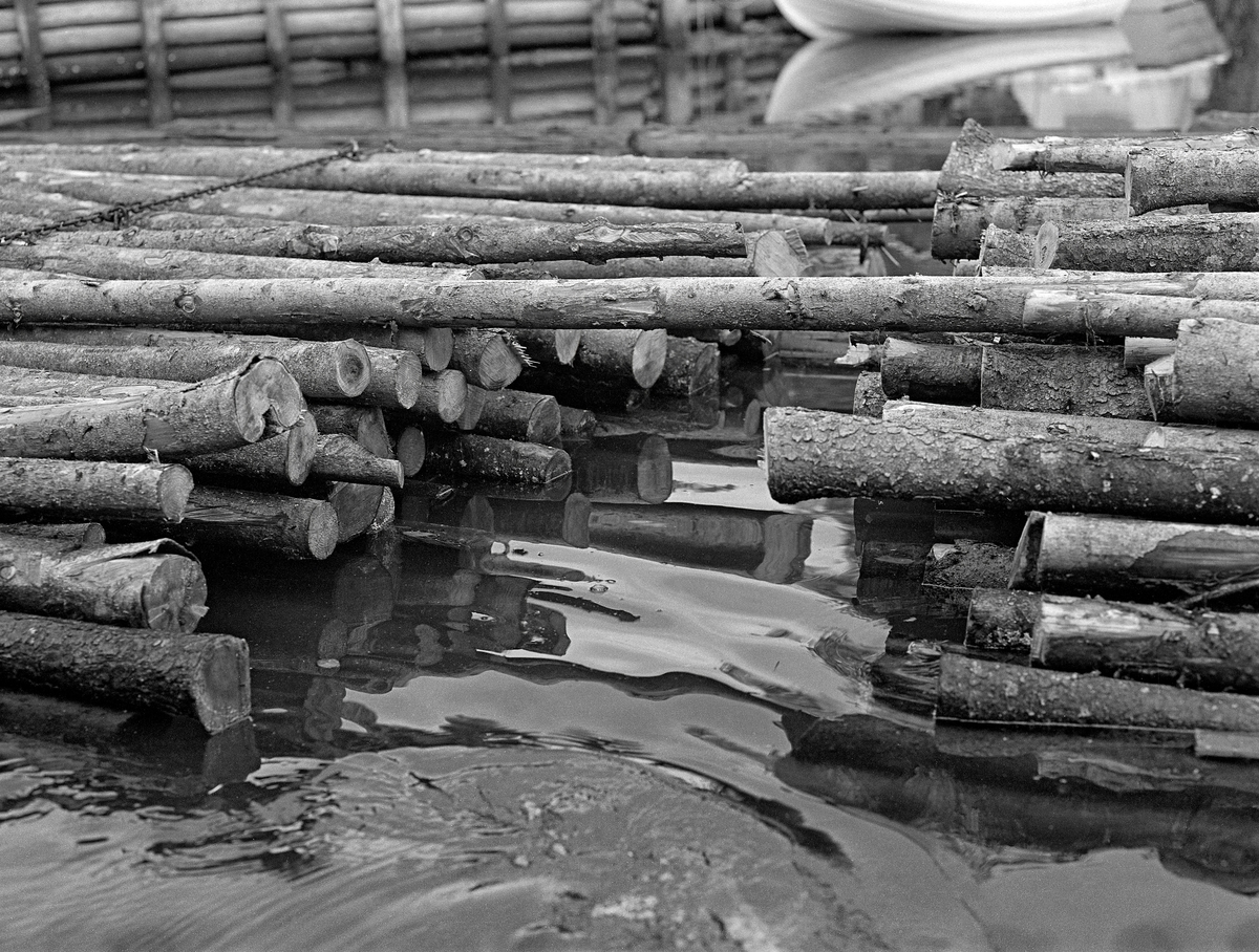 Tømmerbunter ved Strømsfoss sluse i Strømselva i Aremark i Østfold.  Fotografiet er tatt i 1982, den siste sesongen det foregikk tømmerfløting i Haldenvassdraget.  De tre siste åra ble det utelukkende levert ubarket slipvirke (papirråstoff) i tre meters lenger.  Tømmeret ble utislått som bunter fra tømmerbiler.  Deretter ble tømmerbuntene buksert over de store innsjøene i digre slep.  Ved passering av sluser måtte imidlertid slepene deles opp i kortere lenker som fikk plass i slusekamrene.  Av det nevnte tømmersortimentet gikk det vanligvis fire bunter i hver slusevending.  For å kople sammen buntene ble et par stokker trukket fra den øvre delen av en bunt over i den tilstøtende og naglet fast ved hjelp av kramper ved det nærmeste vaierbindet der.

En liten historikk om tømmerfløting og kanaliseringsarbeid i Haldenvassdraget finnes under fanen «Opplysninger».