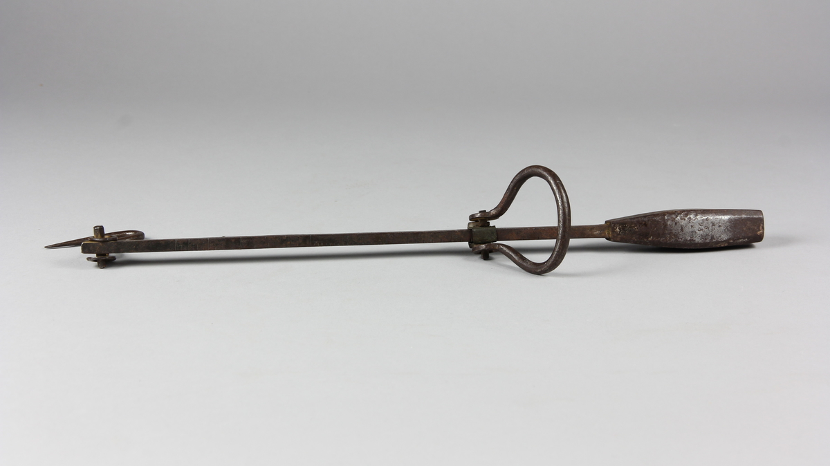 Besman av järn med krok och handtag. Åttkantig klump krönt med år 1836, 26, 9 och justerarmärke TM. Fyrkantig stång med skala fem skålpund.