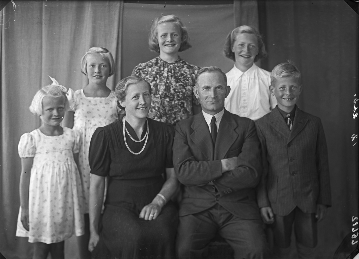 Gruppebilde. Familiegruppe på syv. Kvinne og mann sittende foran, fire piker og en gutt stående bak. Bestilt av Hr. lensmand Robberstad