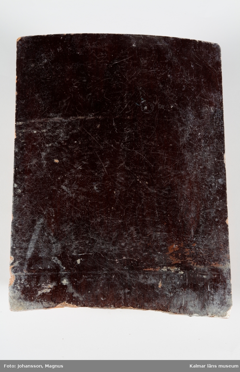 KLM 28165:1:1-8. Kakelugn. Rund ugn med rödbrun glasyr, heltäckande reliefdekor med geometriska mönster och bladmotiv. Tillverkad av gulröd lergodslera. Drejad rump. Datering, 1870-tal.
Förteckning över ugnens samtliga delar, med mått inom parentes, gjord i samband med inventering 1964:
:1. 17 st fasadkakel (29,5x23,5 cm)
       1            -"-     (30x23,5 cm)
       1            -"-     (27,5x23,5 cm)
       2            -"-     (24,5x23 cm)
       4            -"-     (24x23 cm)
       1            -"-     (29x11 cm)
       1            -"-     (31,5x23,5 cm)
       2            -"-     (32x23,5 cm)
       1            -"-     (32x25 cm)
       1            -"-     (31x24 cm)
       1            -"-     (31,5x12 cm)
:2.   6 st livkakel (23,5x25 cm)
:3.   3 st listkakel (6,5x28 cm)
       1       -"-      (6,5x26 cm)
       4       -"-      (12x28 cm)
:4.   1 st krönkakel (23x25 cm)
       3        -"-        (23x28 cm)
       1        -"-        (20x26 cm)    
:5. 11 st kakelfragment
:6.   2 luckor av järn samt ram, 30,5x27 cm.
:7.   3 sotluckor av mässing och järn, dia: 10,5 cm.
:8.   1 spjäll av järn, 53,5x15 cm.
