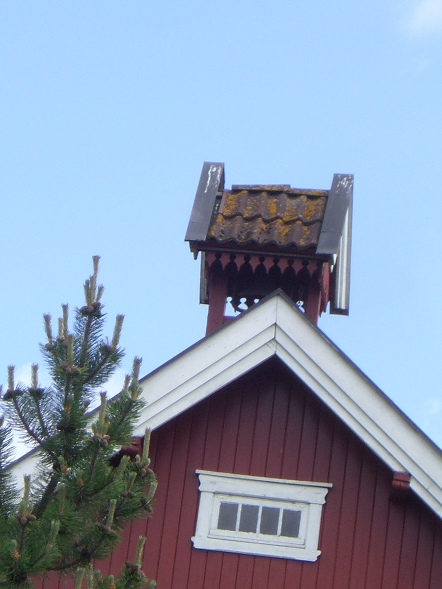 Klokketårnet på Rustad store har enkelt saltak og sveitserstildetaljer. Tårnet er plassert på stabburet, og er i middels stand.