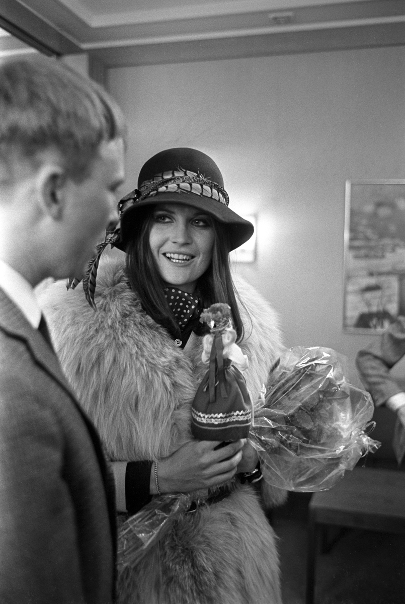 Den britiske popartisten Sandie Shaw ankommer Fornebu Lufthavn i anledning et besøk i Holmenkollen hvor hun skal vise sko. Her får hun overrakt en dukke i Haradanger-bunad.