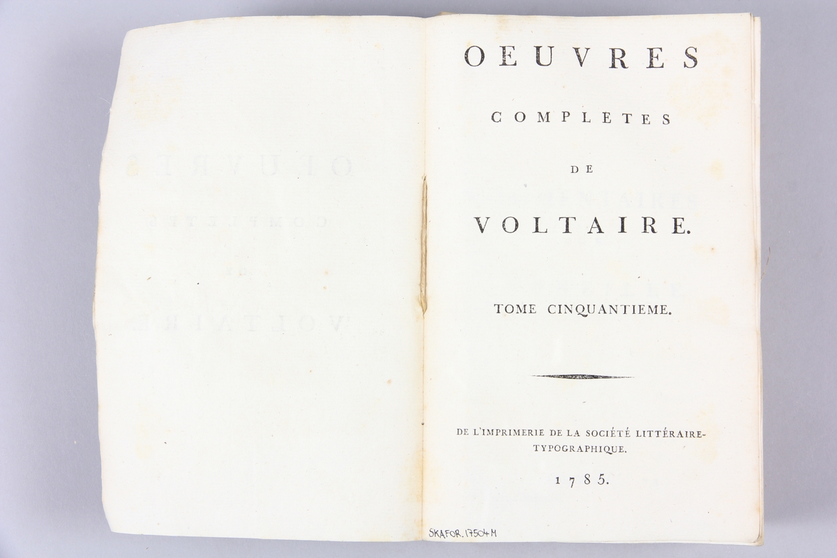 Bok, pappband,"Oeuvres complètes de Voltaire." del 50, tryckt 1785.
Pärm av gråblått papper, skurna snitt. Blekt rygg med pappersetikett med tryckt text med volymens namn och nummer.