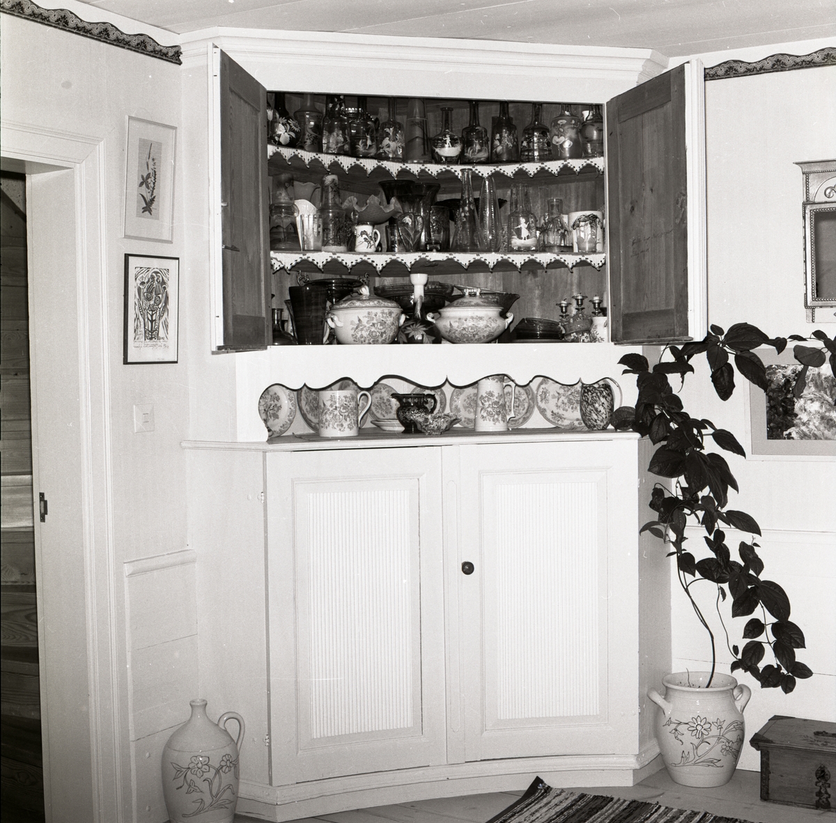 I ett rum på gården Sunnanåker står ett öppet skåp fyllt med glas och porslin, 1972.