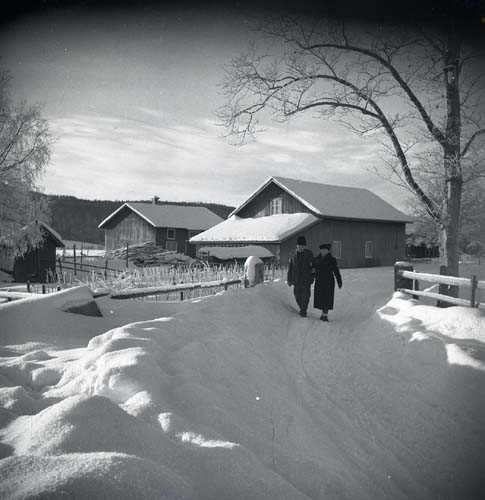 En man och en kvinna promenerar längs en snöig väg, 1948.