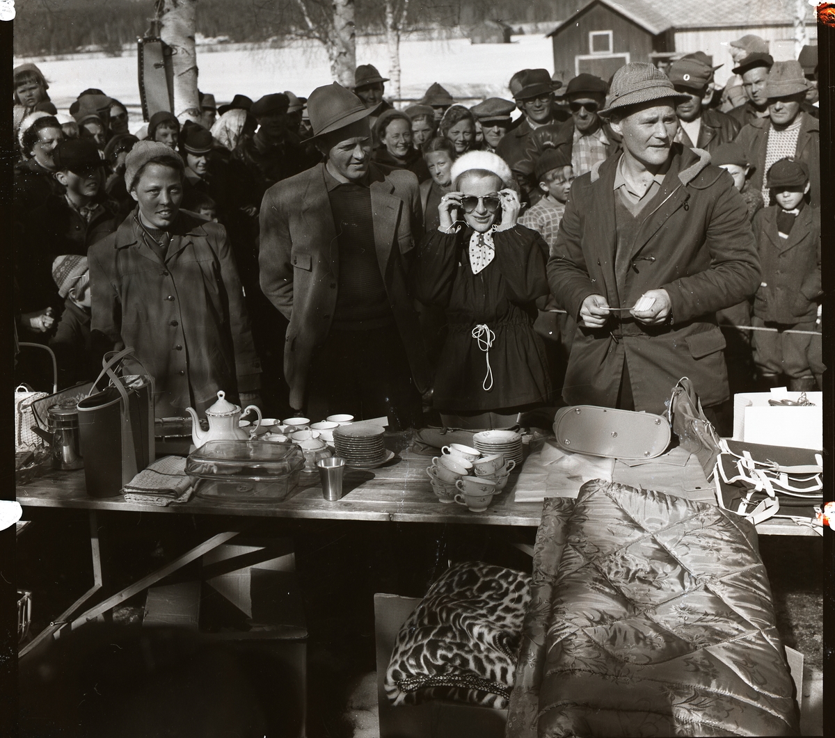 Pristagare vid pimpeltävling med 330 deltagare på Hölesjön 22 april 1956. Publik och deltagare tittar på föremålen på prisbordet.