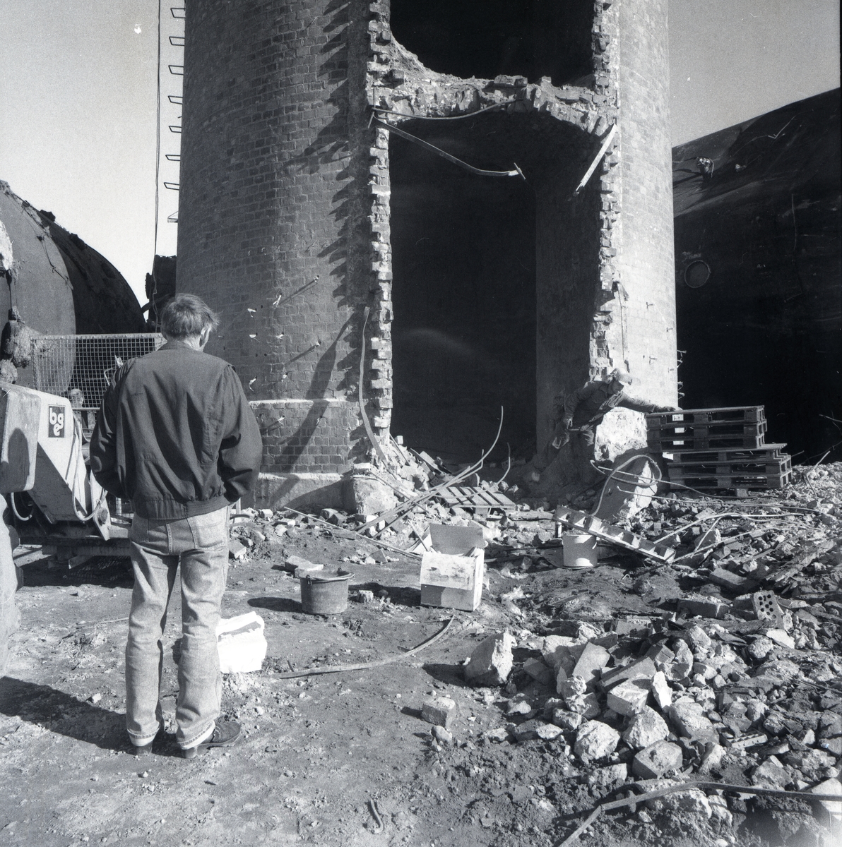 En halvriven tegelbyggnad vid rivningen av Marmafabriken. En man står och studerar arbetet.