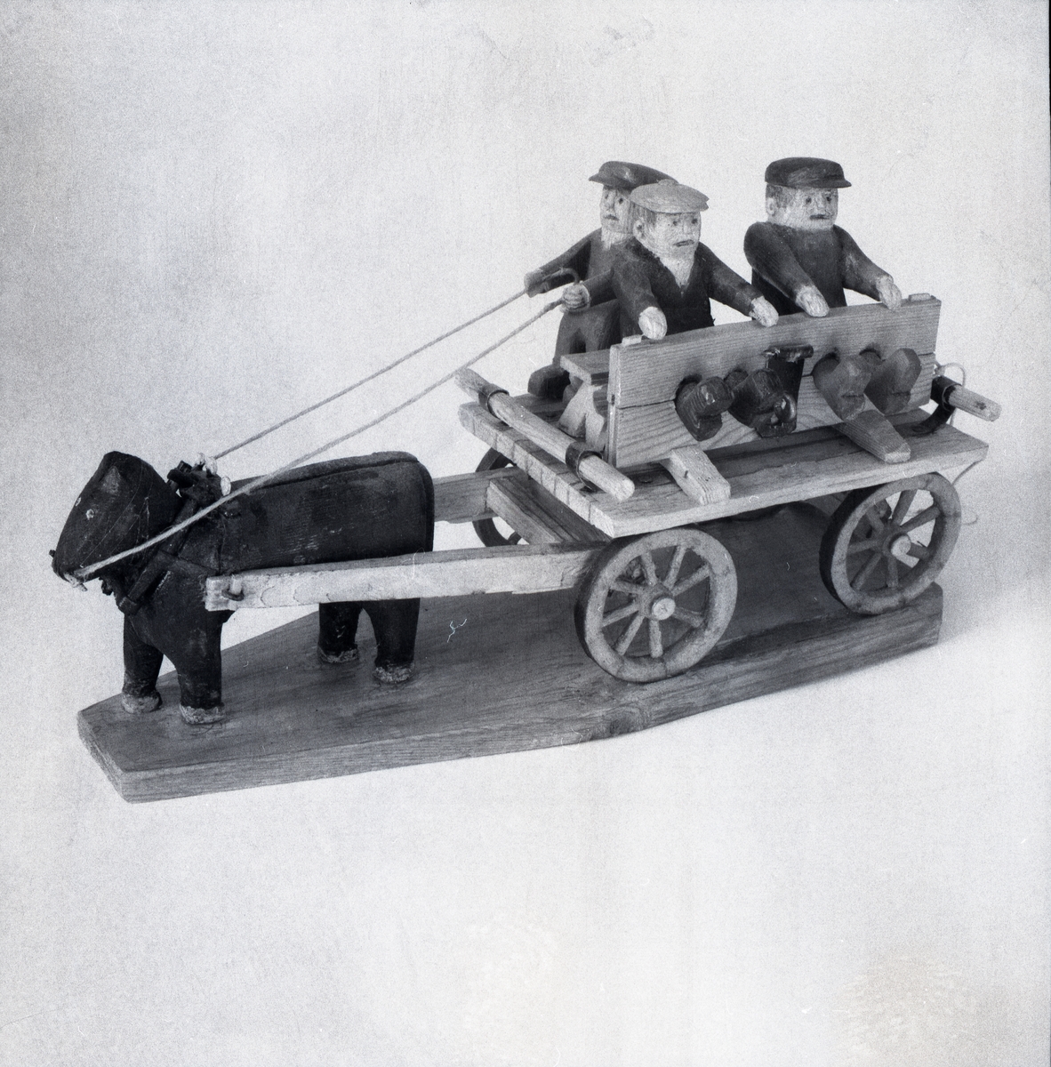 En modell föreställande tre figurer på en vagn som blir dragen av en häst.