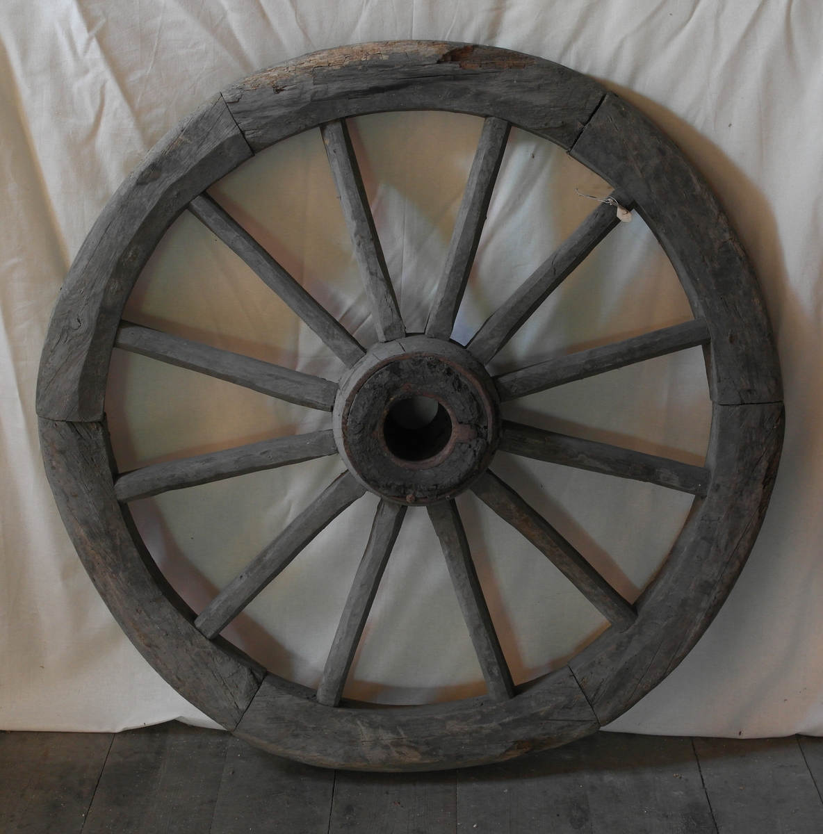 Kjerrehjul med trestokk. Hjulet er i saget og hugget eik, og smidd jern. Navet er jernbeslått. Hjulringen er satt sammen av 6 deler.