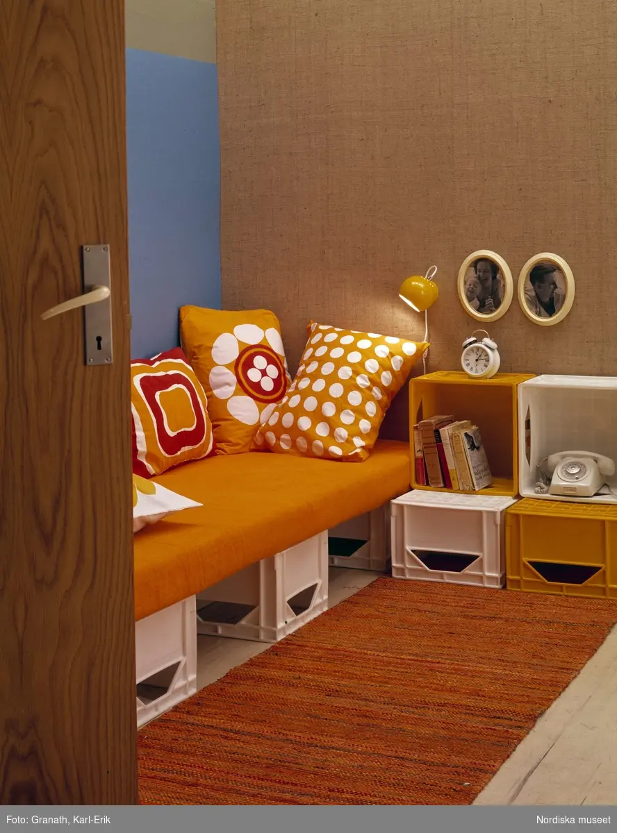 Interiör; soffa på dryckesbackar av plast. Orange textil.