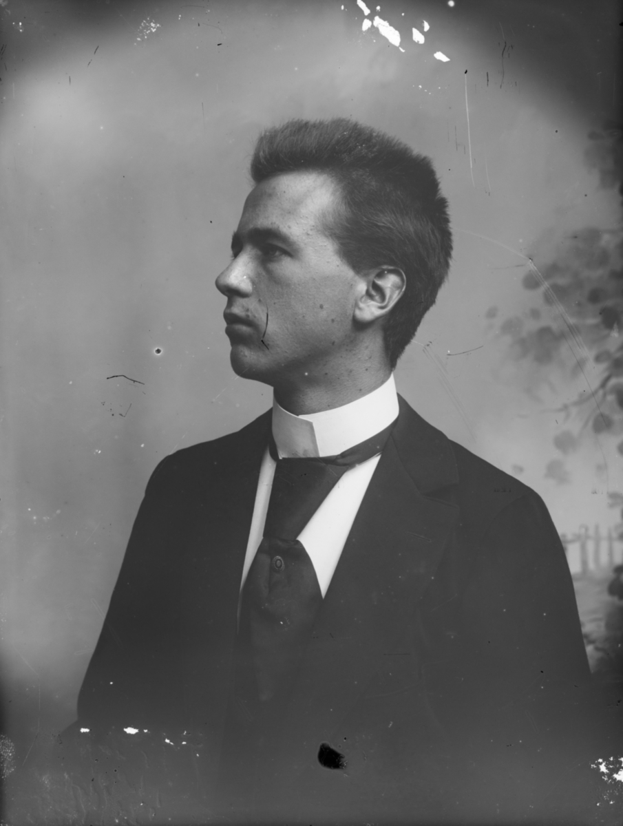 Portrett av yngre mann med mørk dress, atelierfoto